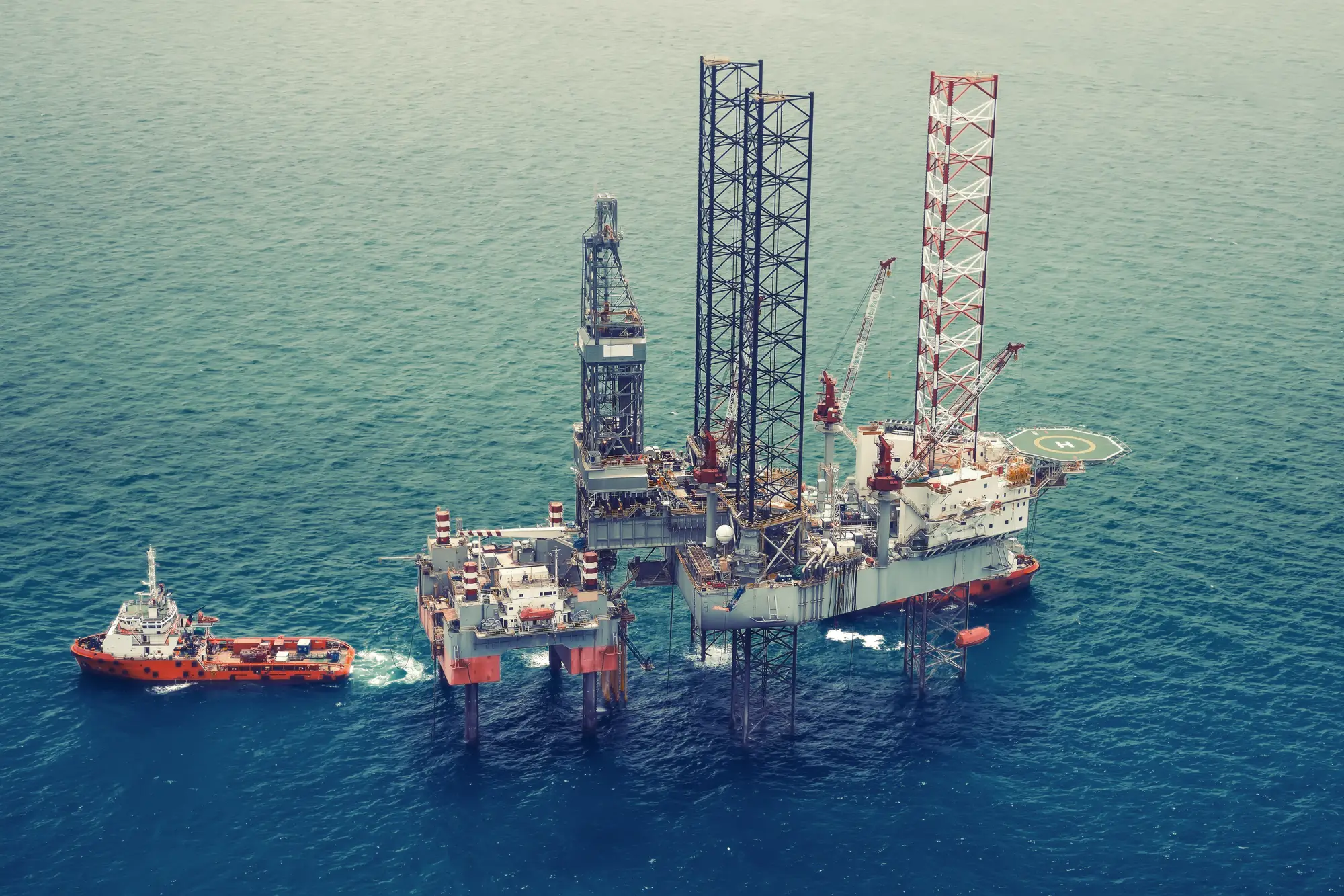 Offshore oljerigg med forsyningsskip i åpent hav
